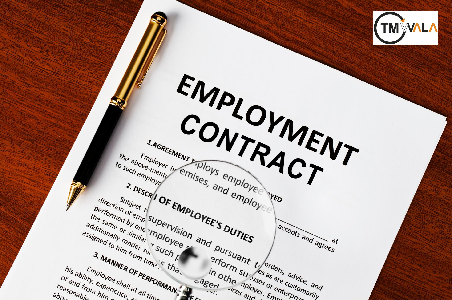 Employment contract document with pen and magnifying glass on wooden desk.
